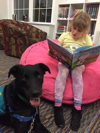 Emily reads “How Rocket Learned to Read” by Tad Hills to Koda-the-Sidekick at a recent Reader of the Pack session at Orono Public Library. CREDIT: Photo courtesy Stacey Coventry.
