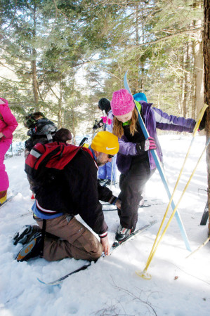 Tim Pearson the Dedham School Physical Education and Health teacher in Holden, helps one of the fifth grade students with a ski during a Cross Country Ski outing on the school trails on Monday, March 20. Photo by Terry Farren